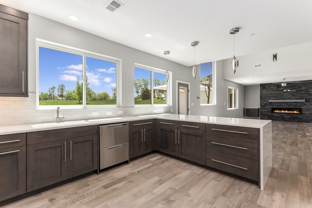 Spacious modern living room with stone fireplace, large windows, and stylish lighting fixtures.