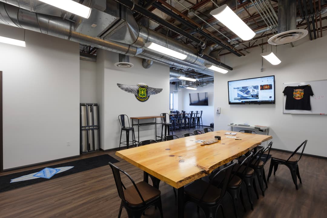 Modern meeting room with a large wooden table, tech setup, and creative decor.