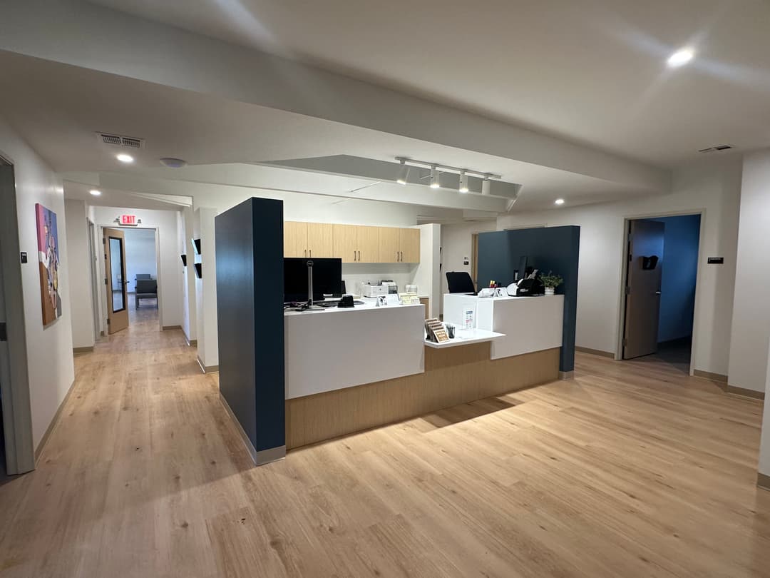 Modern office reception area with light wood flooring and contemporary design elements.