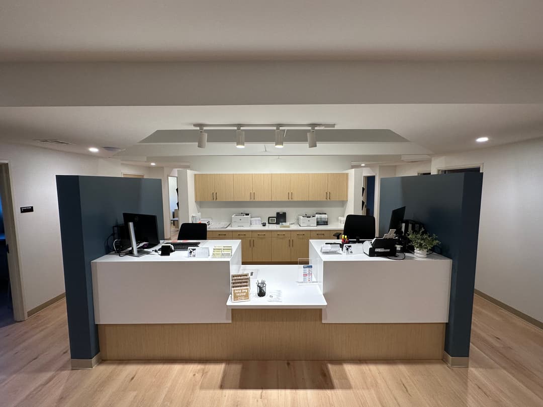 Modern office reception area with desks, computers, and a clean, minimalist design.