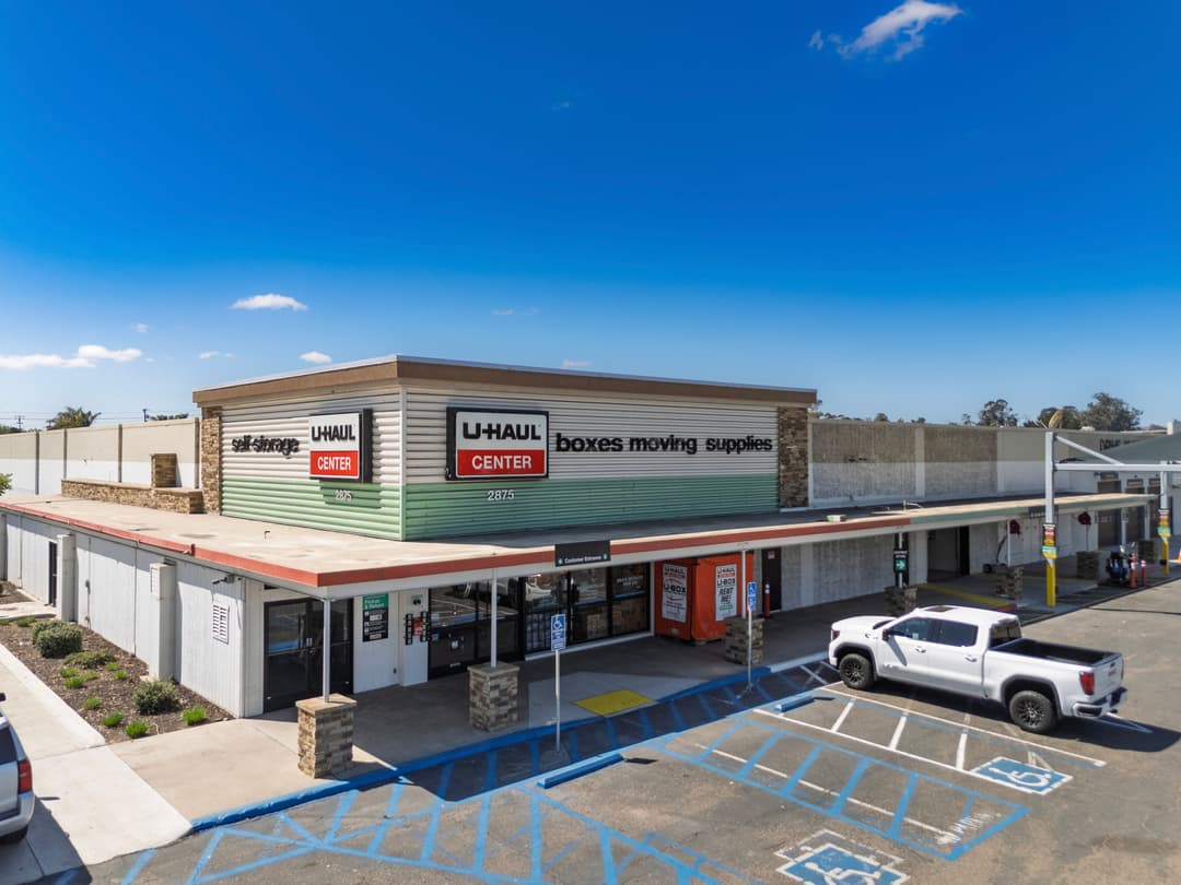 U-Haul Center with moving supplies and parking lot, bright sky overhead.