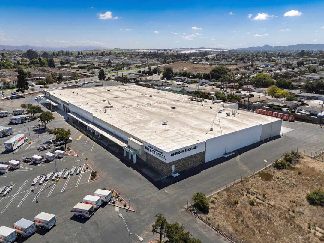 Aerial view of a self-storage facility with trucks parked outside in a suburban area.