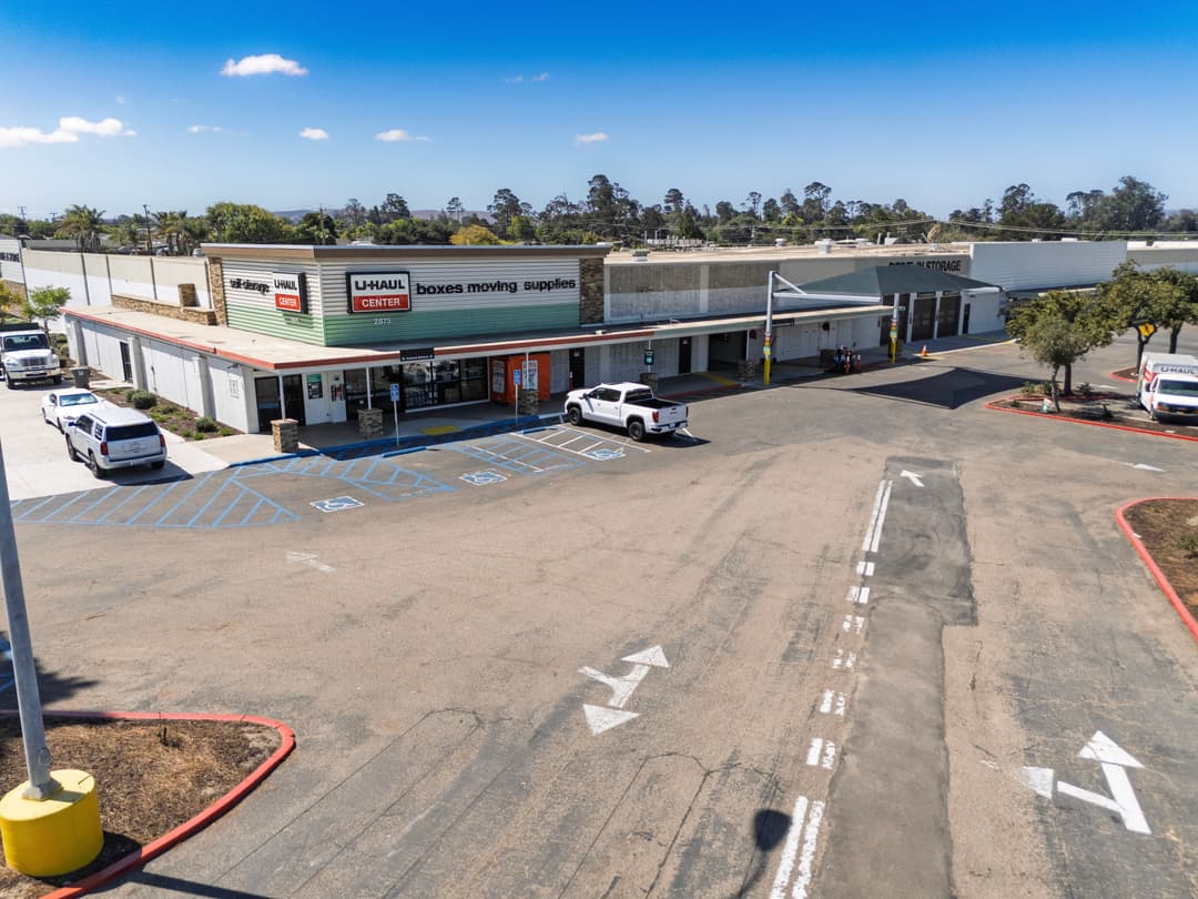U-Haul Center parking lot with moving supplies and trucks, sunny day, clear blue sky.