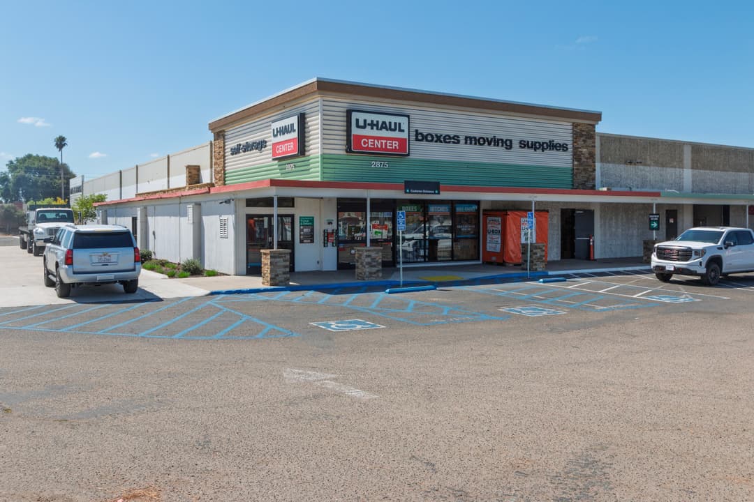 U-Haul Center storefront with parking, boxes, and moving supplies, clear blue sky.