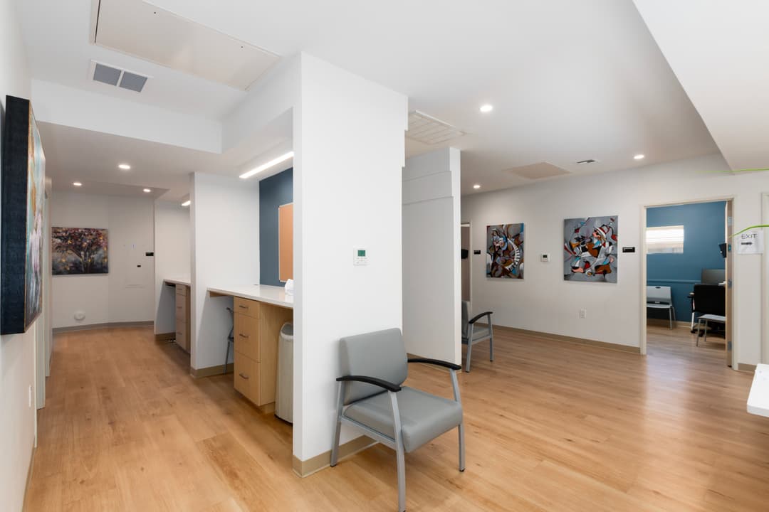 Modern medical office interior with seating, artwork, and bright lighting.
