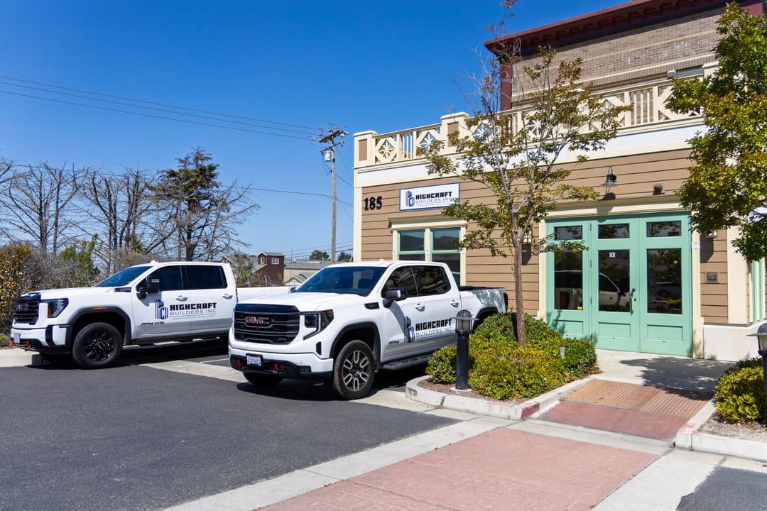Two pickup trucks with "Highcart" branding parked outside a commercial building on a sunny day.
