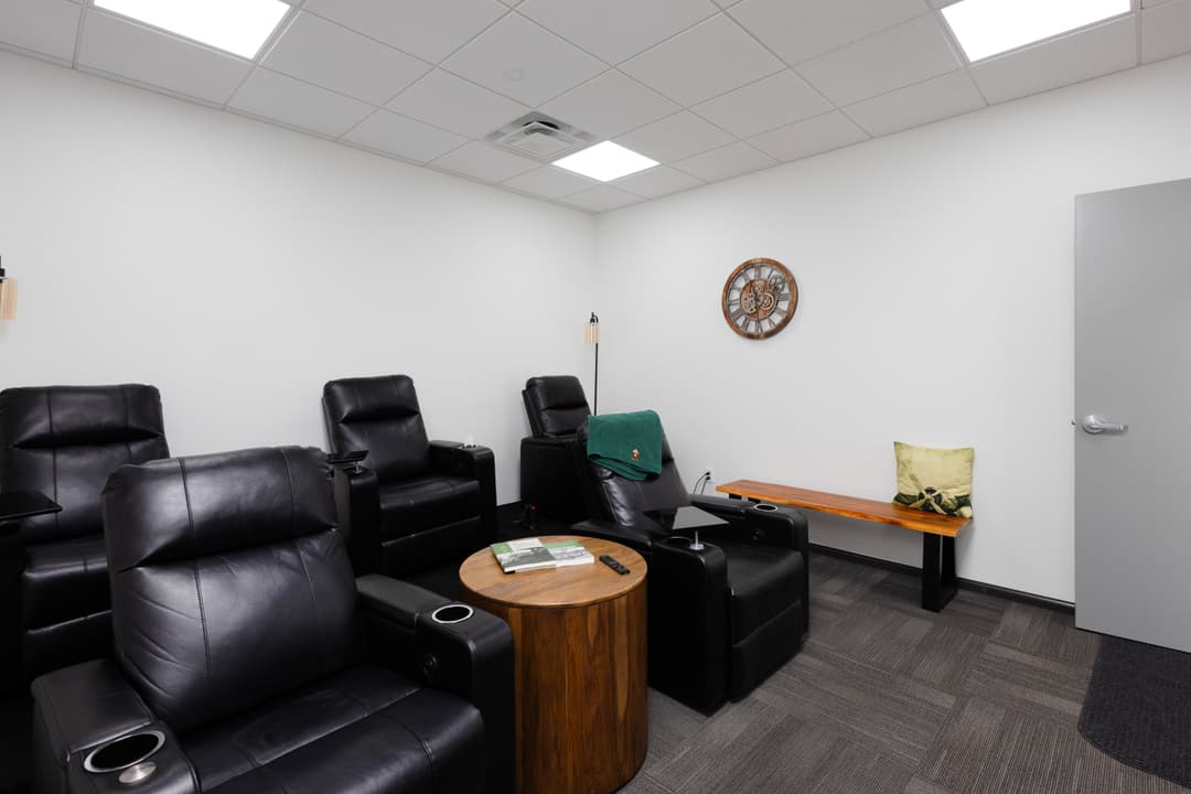 Cozy relaxation room with black reclining chairs, wooden accents, and soft lighting.