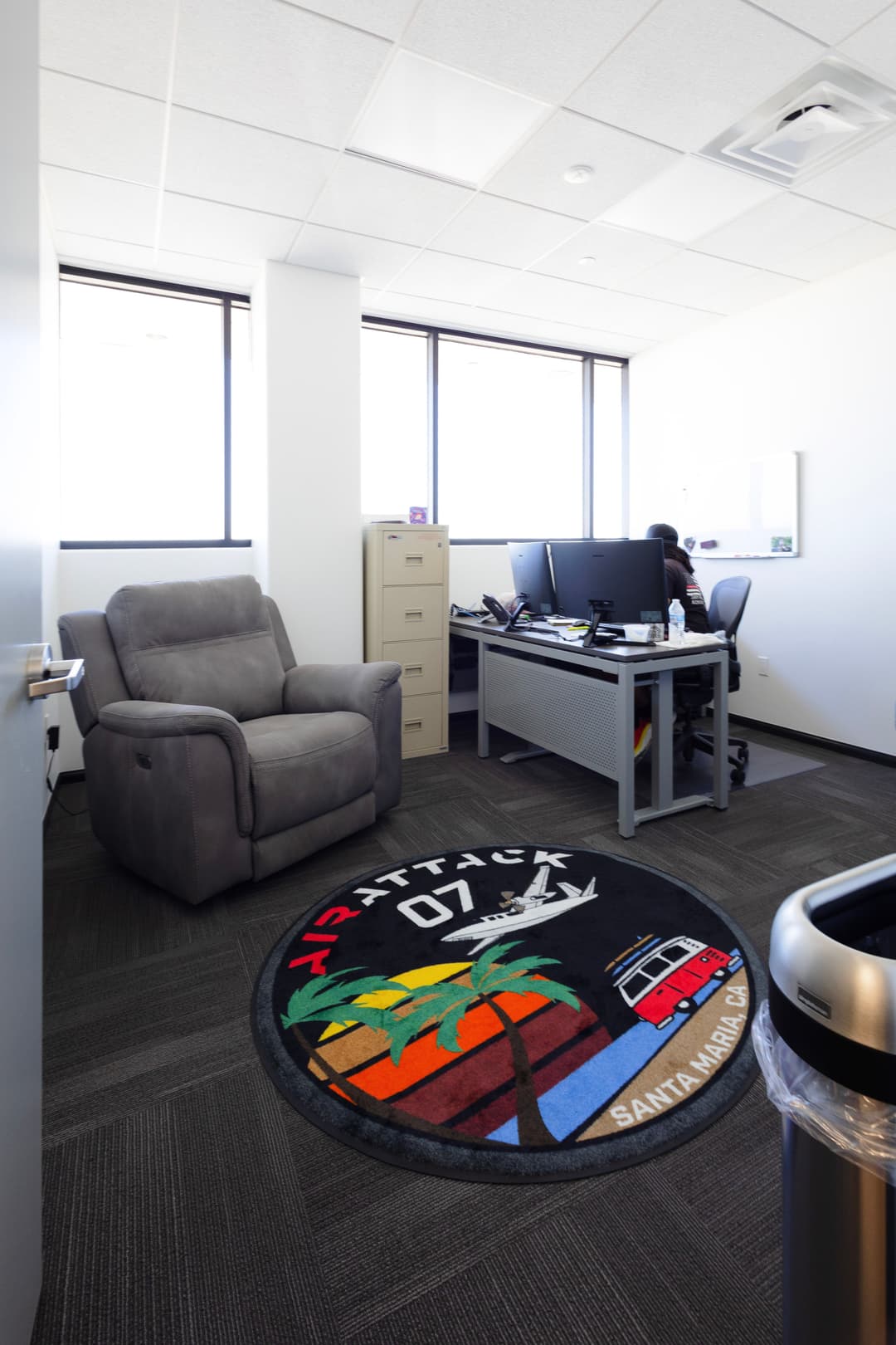 Modern office space featuring a cozy armchair, workstation, and a decorative rug.