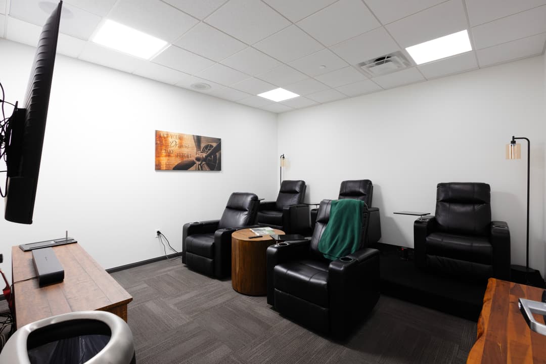 Relaxing lounge with black recliners, wooden tables, and a guitar-themed wall art.