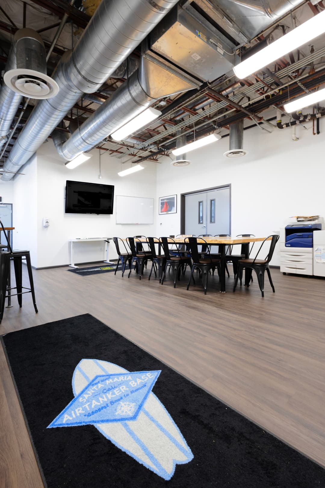 Modern meeting room with sleek design, air conditioning vents, and surfboard-themed rug.