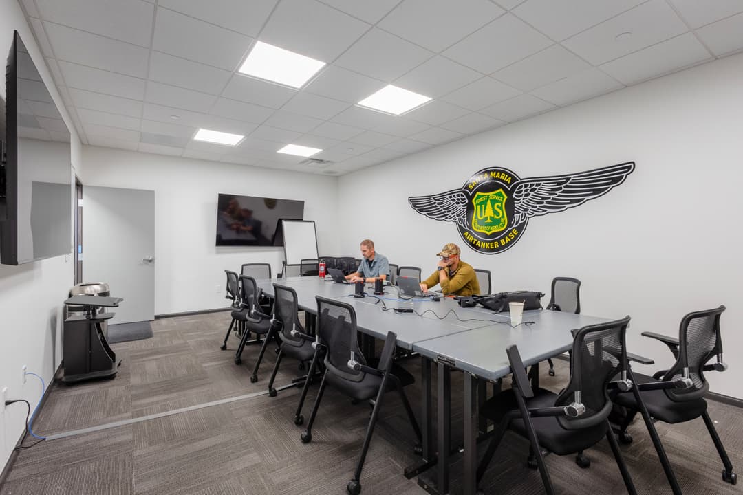 Two people in a modern conference room with UAS logo on the wall, discussing strategy.