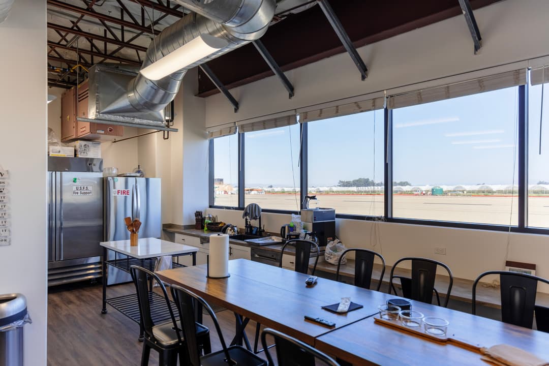 Modern kitchen workspace with industrial design, large windows, and dining area.