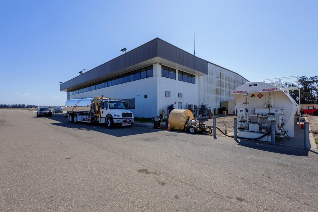 Fueling station with trucks and equipment at an airport under a clear blue sky.