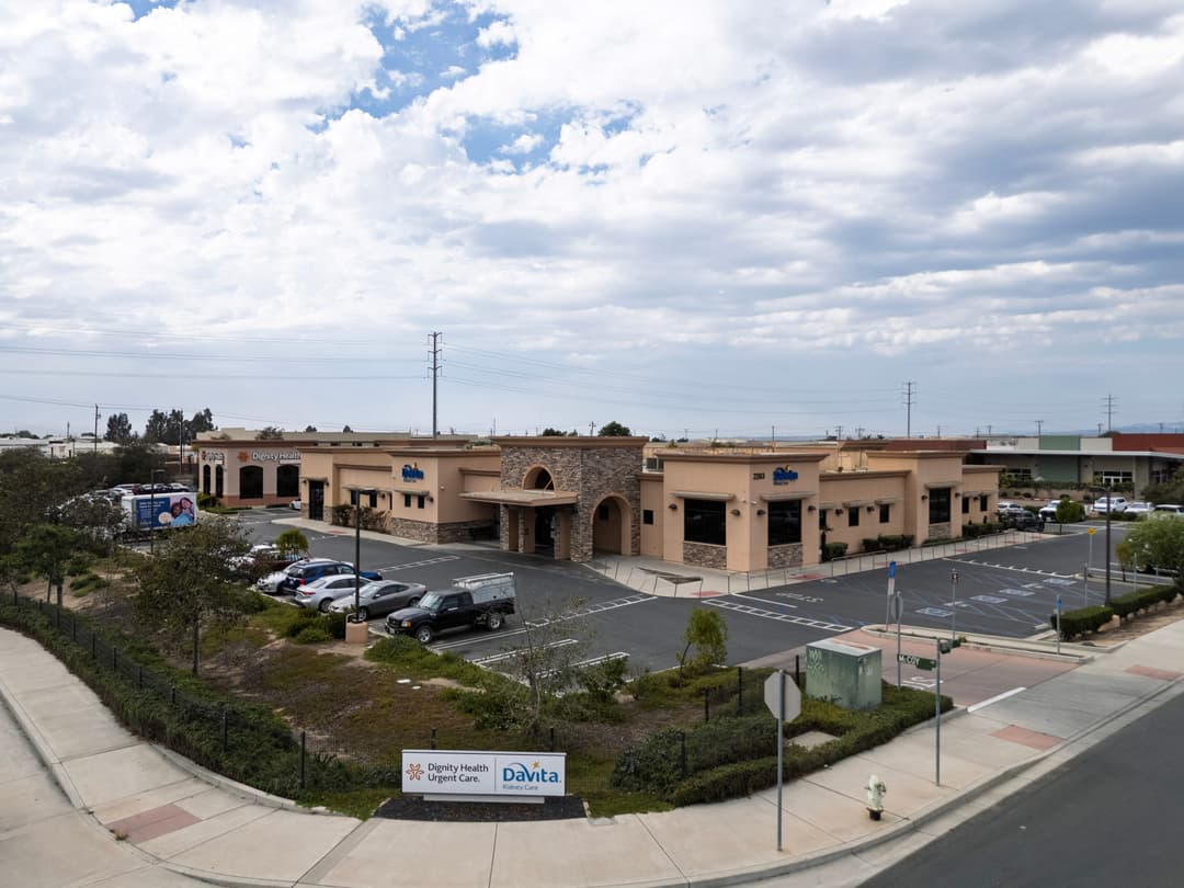 Aerial view of a healthcare facility with parking and signage for Dignity Health and DaVita.