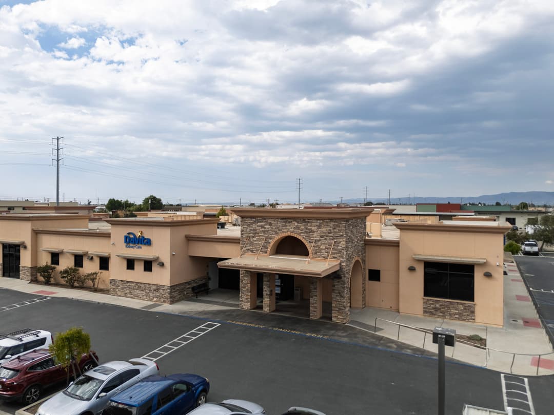 Exterior view of a Datica building with stone accents and cloudy sky background.