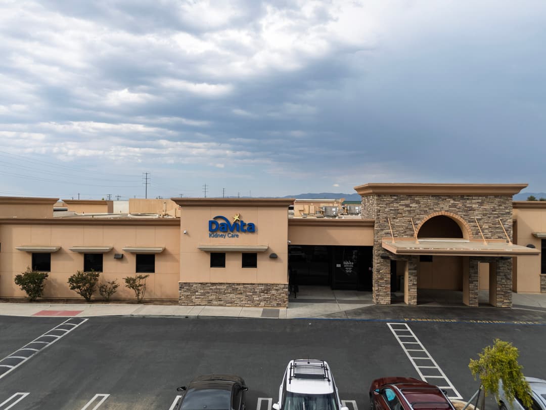 DaVita Kidney Care facility with modern architecture and parking lot, under a cloudy sky.
