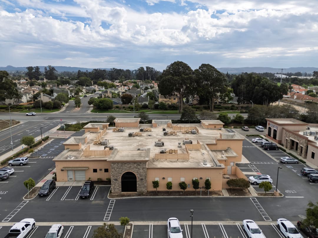 Aerial view of an empty commercial building surrounded by parking and residential areas.
