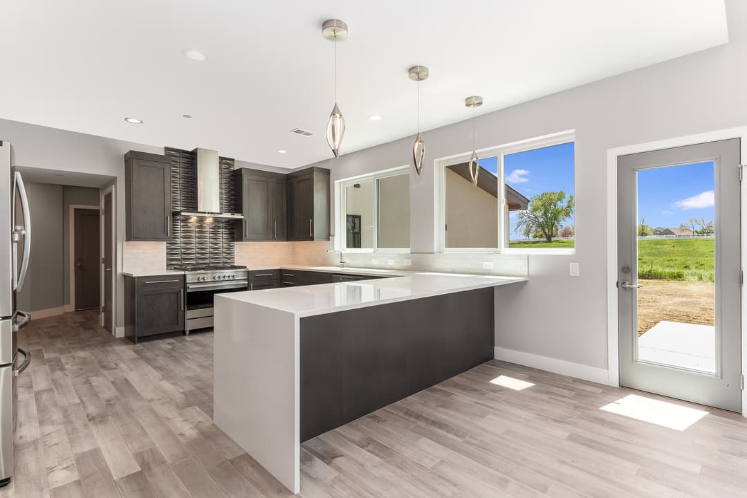 Modern kitchen with dark wood cabinetry, stainless steel appliances, and open layout.