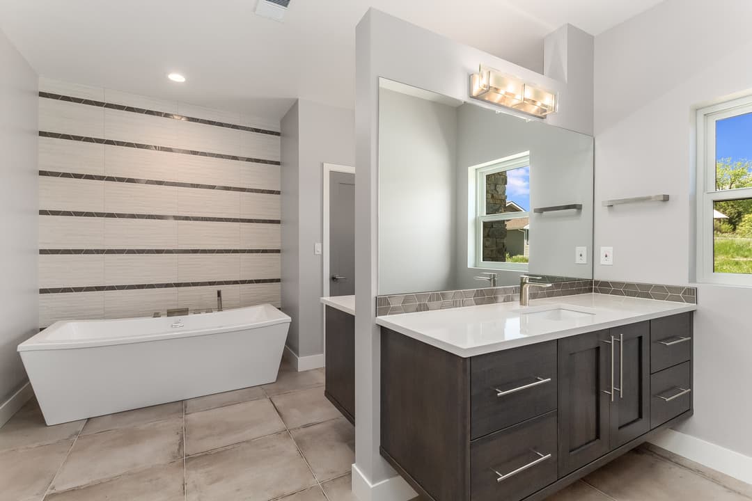 Modern bathroom with freestanding tub, stylish vanity, and elegant tile accents.