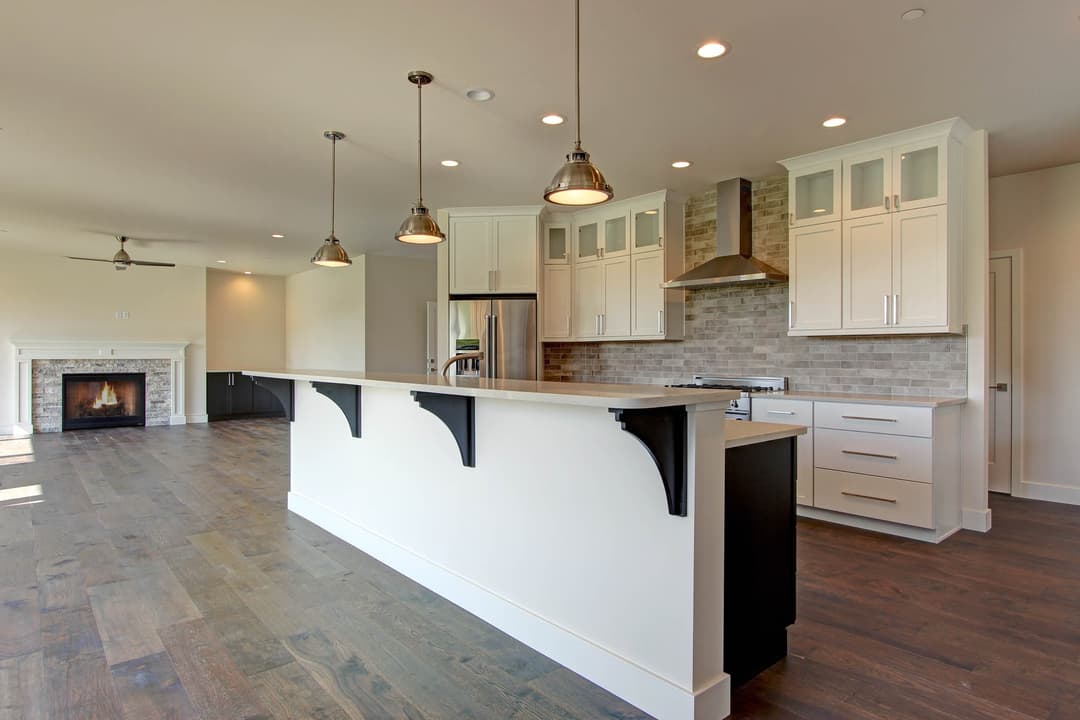 Modern kitchen featuring white cabinets, pendant lighting, and a large island with a dark base.