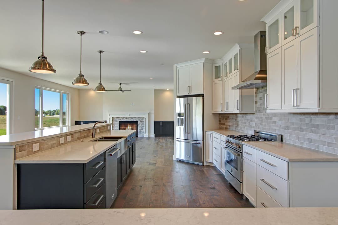 Modern kitchen with stainless steel appliances, white cabinets, and hardwood flooring.