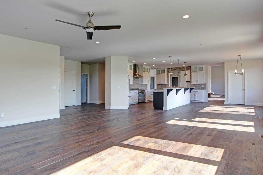 Spacious modern living room with hardwood floors and open kitchen design, featuring stylish lighting.