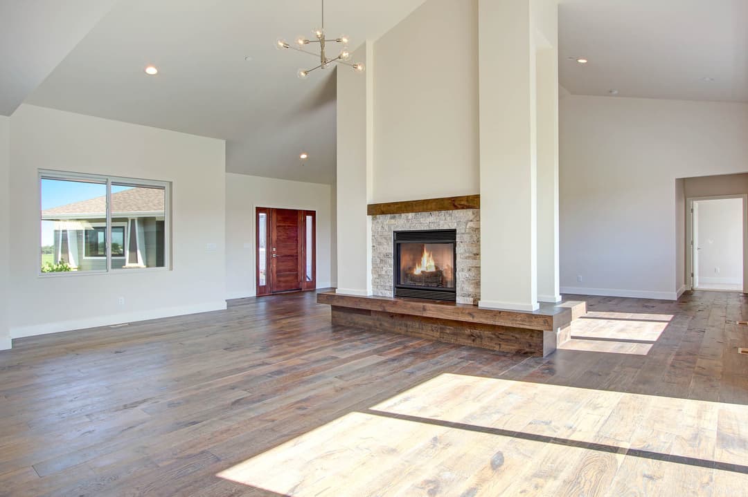 Spacious modern living room with a fireplace, large windows, and hardwood flooring.