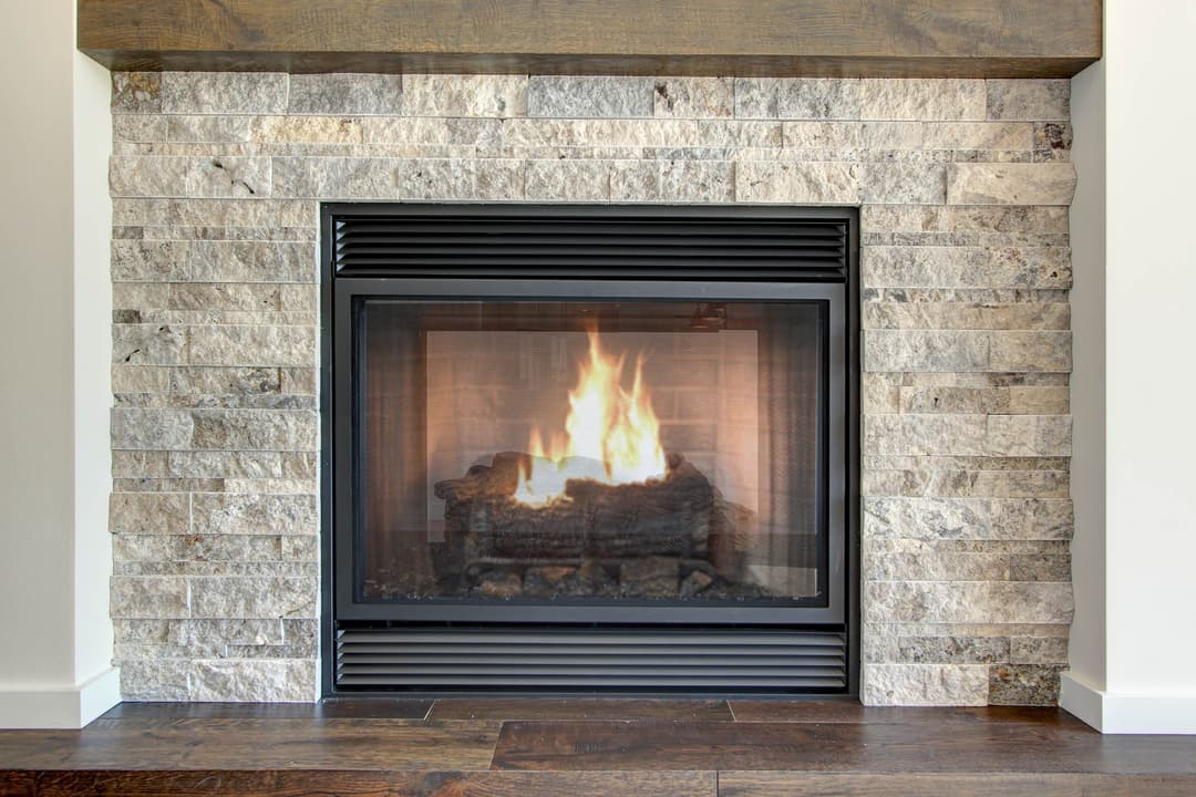 Modern fireplace with stone surround and glowing flames in a cozy living room setting.