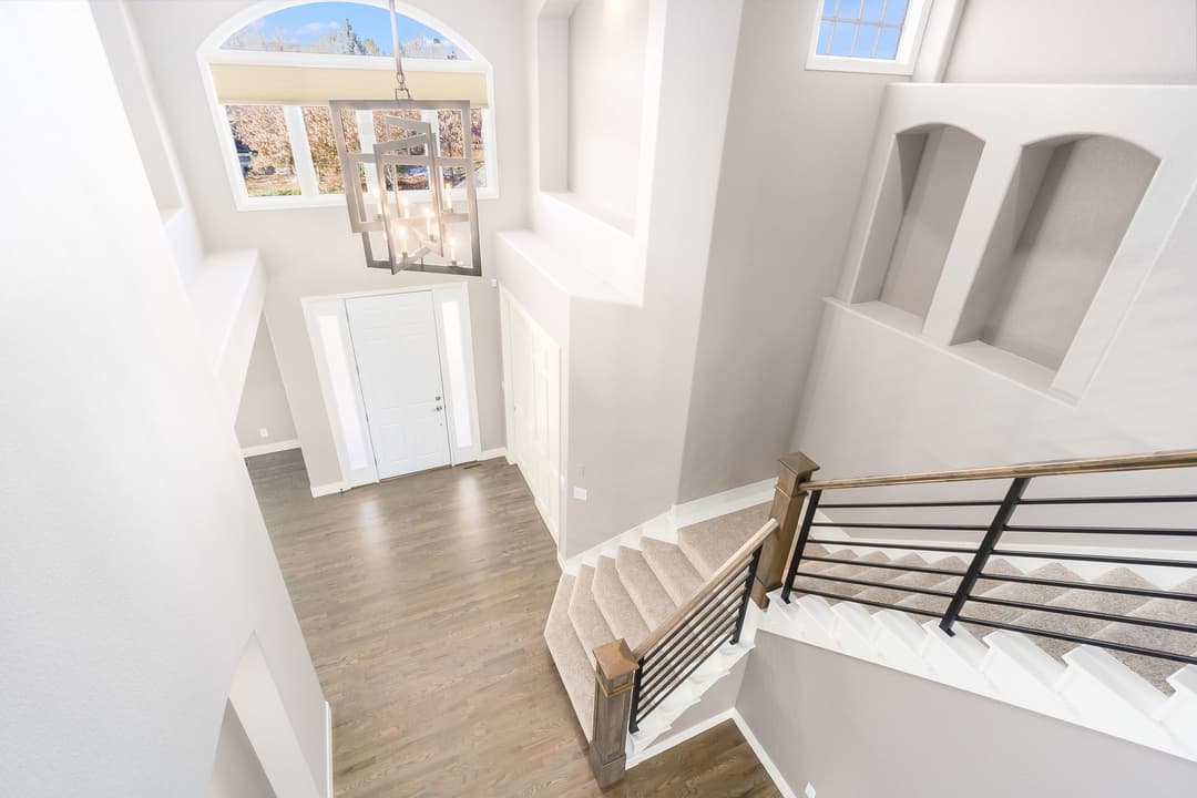 Spacious modern foyer with stairs, chandelier, and neutral color palette.