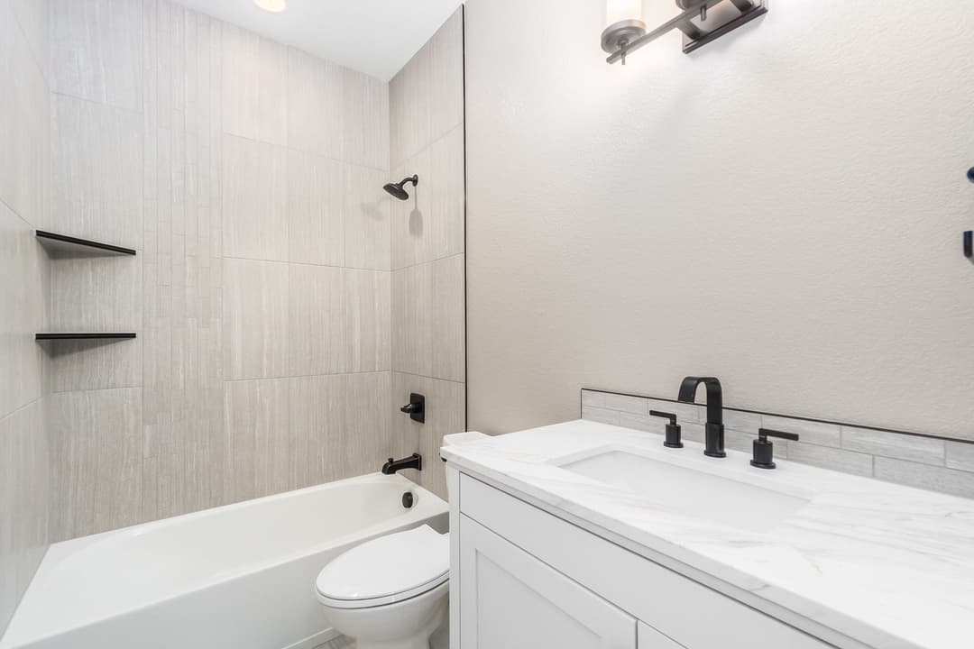 Modern bathroom featuring a sleek tub, minimalist design, and elegant black fixtures.