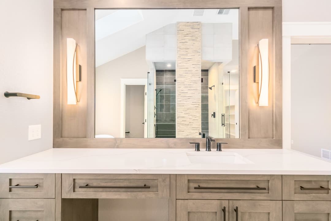 Modern bathroom with a stylish vanity, large mirror, and elegant lighting fixtures.