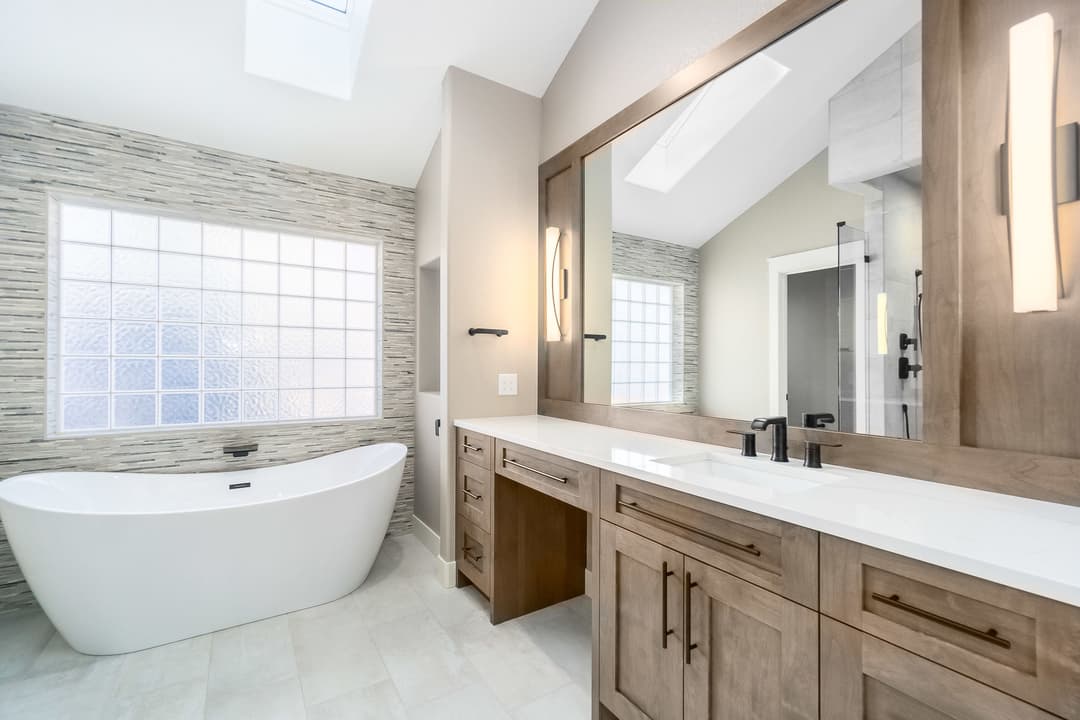 Modern bathroom with freestanding tub, dual sinks, and large window for natural light.