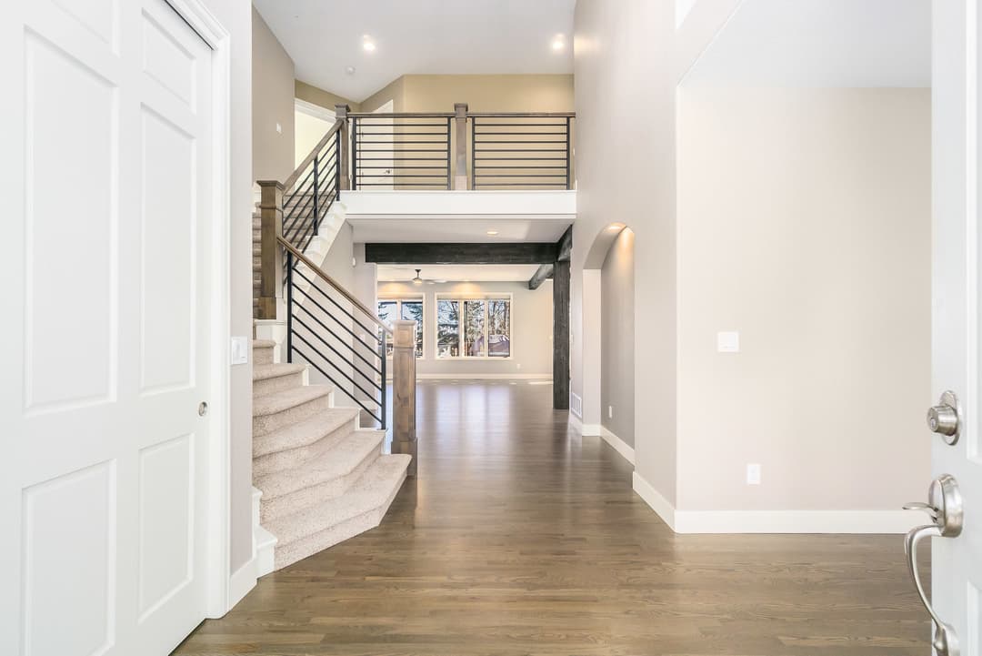 Spacious modern home entryway with staircase, wood flooring, and natural light.