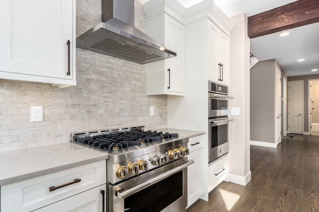 Modern kitchen featuring stainless steel appliances, white cabinetry, and elegant backsplash.