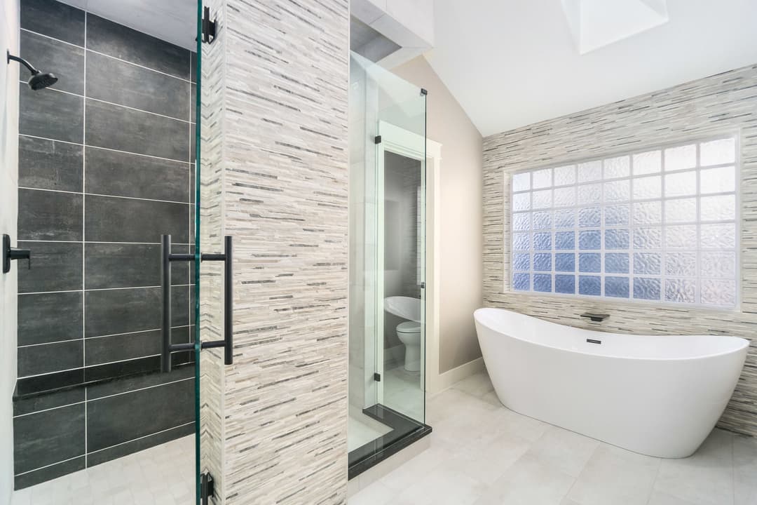 Modern bathroom with glass shower, freestanding tub, and sleek tile accents.