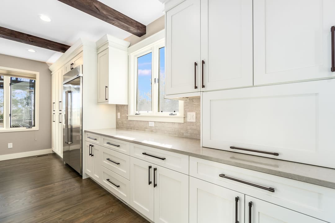 Modern kitchen with white cabinets, grey countertops, and stainless steel appliances. Natural light.