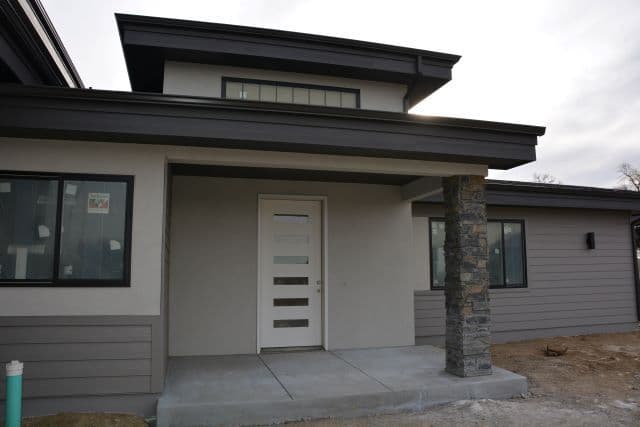 Modern home exterior featuring sleek design, stone accents, and large windows.