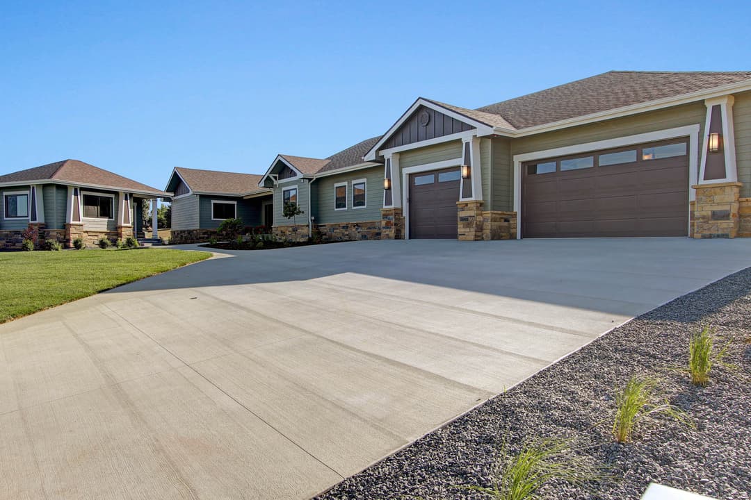 Modern suburban home with stone accents and spacious driveway under clear blue sky.