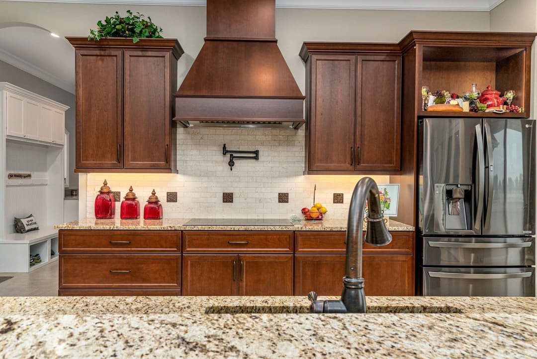 Modern kitchen with dark wood cabinets, a stainless steel fridge, and a stylish granite countertop.