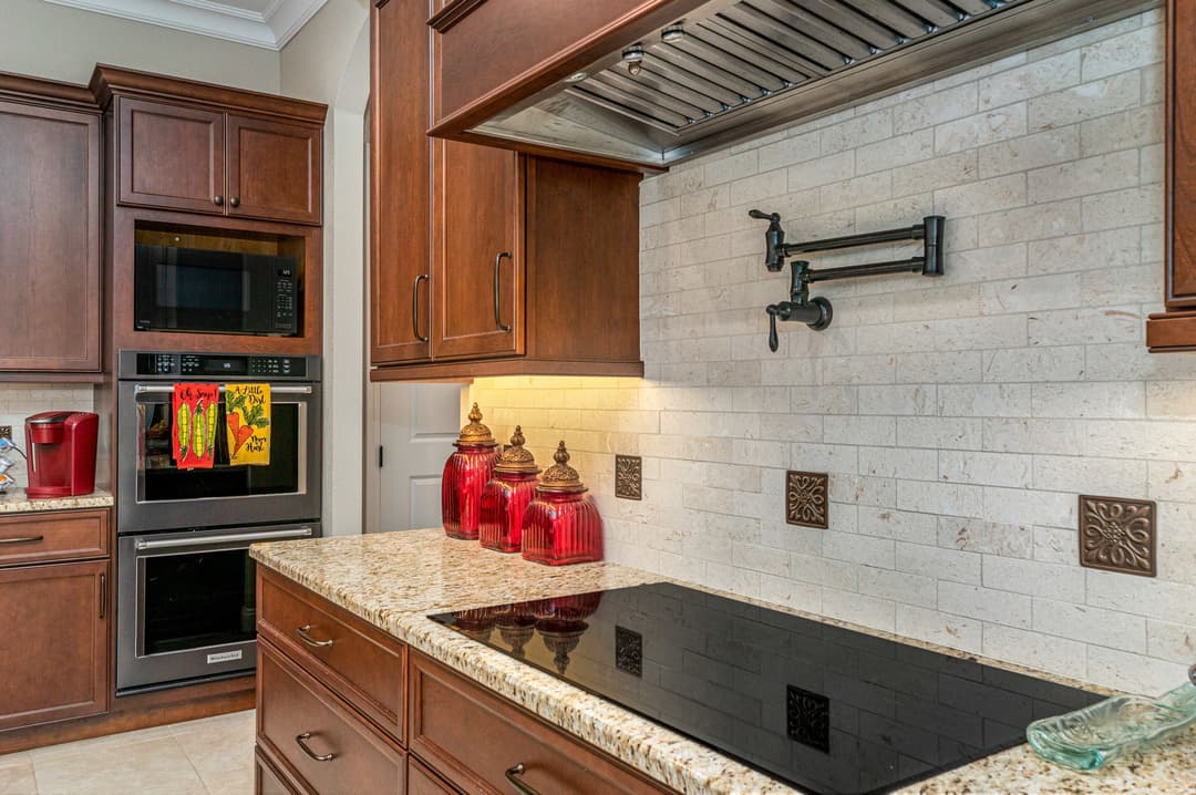 Modern kitchen with brown cabinets, granite countertop, red decor, and sleek appliances.