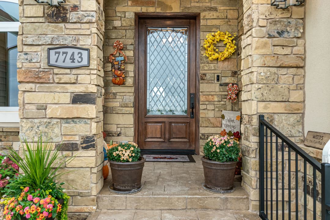 Welcoming front door with stone accents, seasonal decor, and potted flowers at 7743.