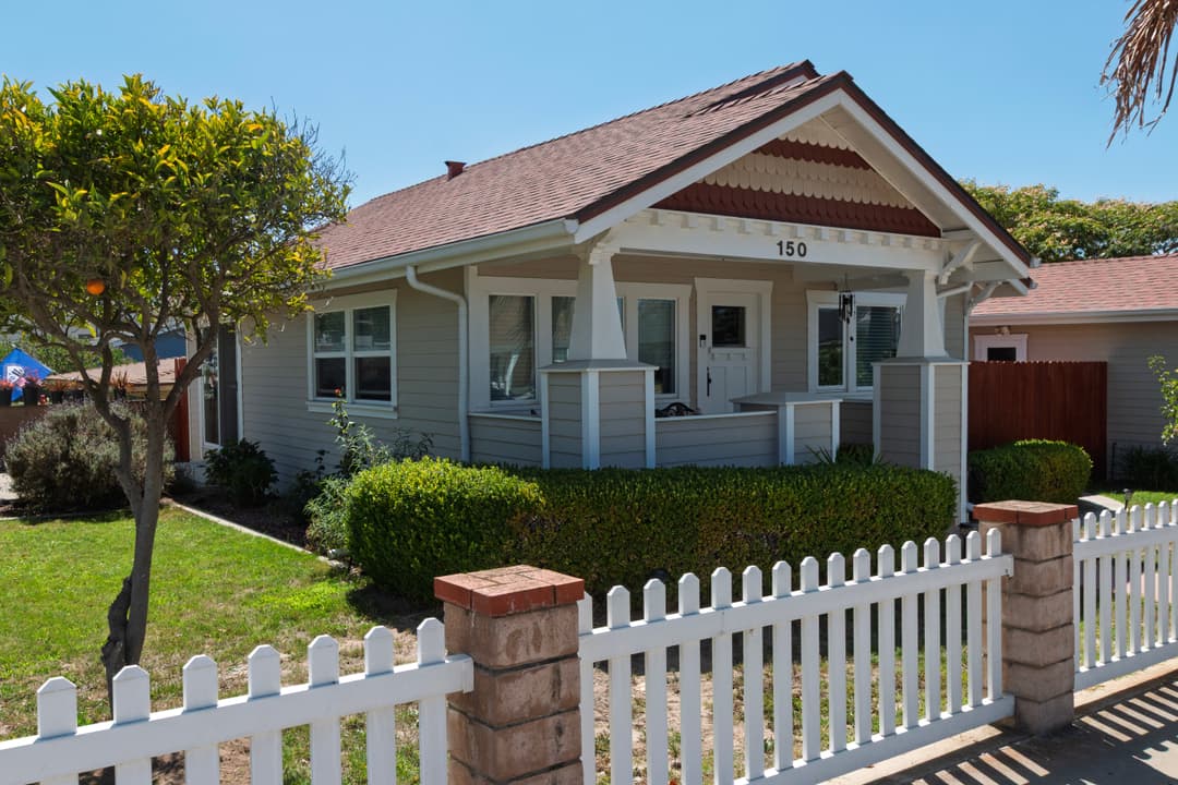 Charming gray house with porch and white picket fence, located at 150 Street.