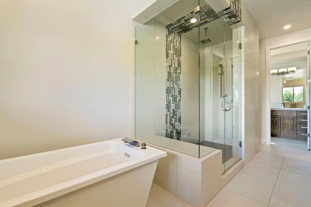 Modern bathroom featuring a glass shower, freestanding tub, and elegant tile design.