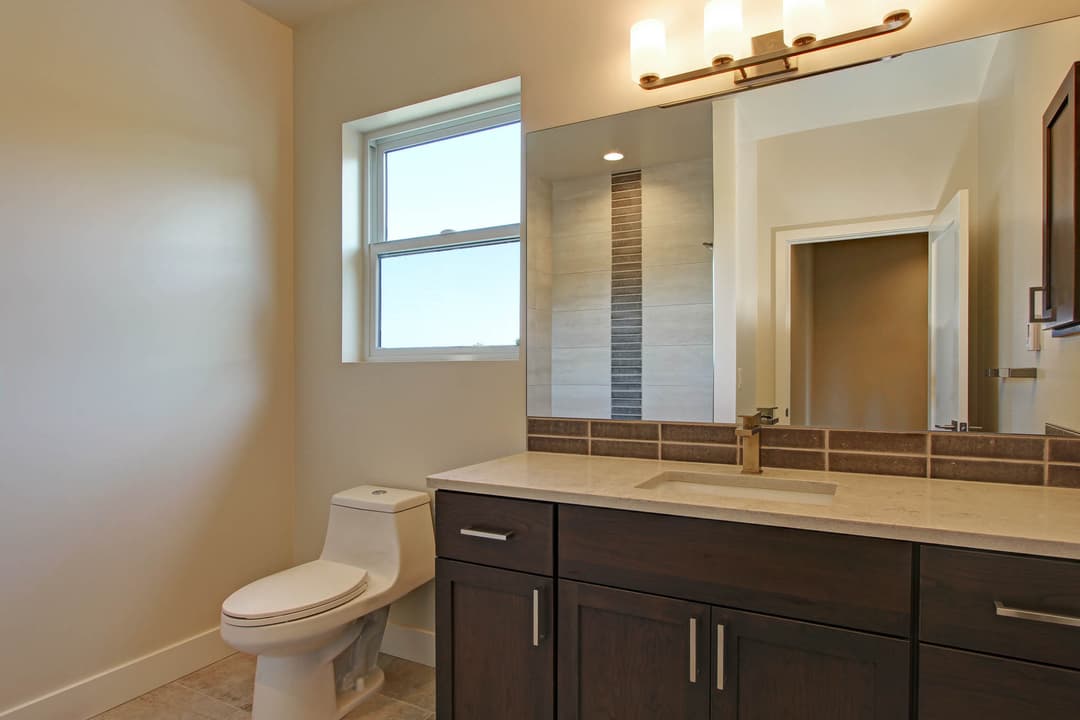 Modern bathroom featuring a window, stylish vanity, and tiled shower area.