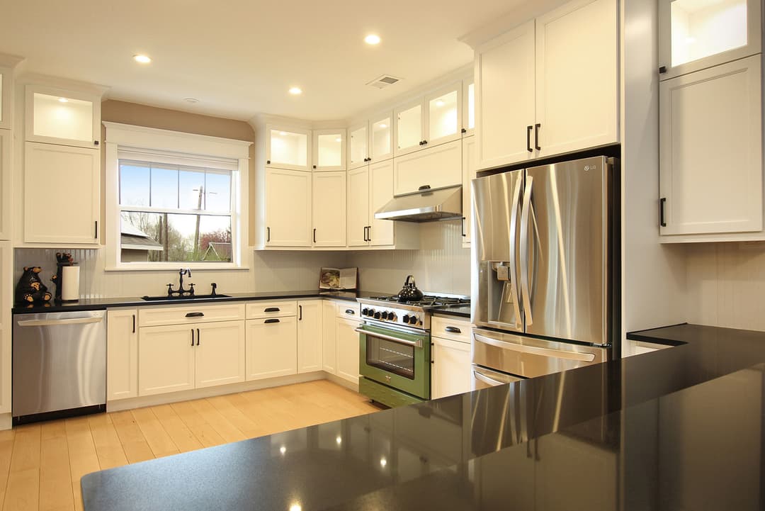 Modern kitchen with white cabinets, stainless steel appliances, and green range. Bright, airy design.