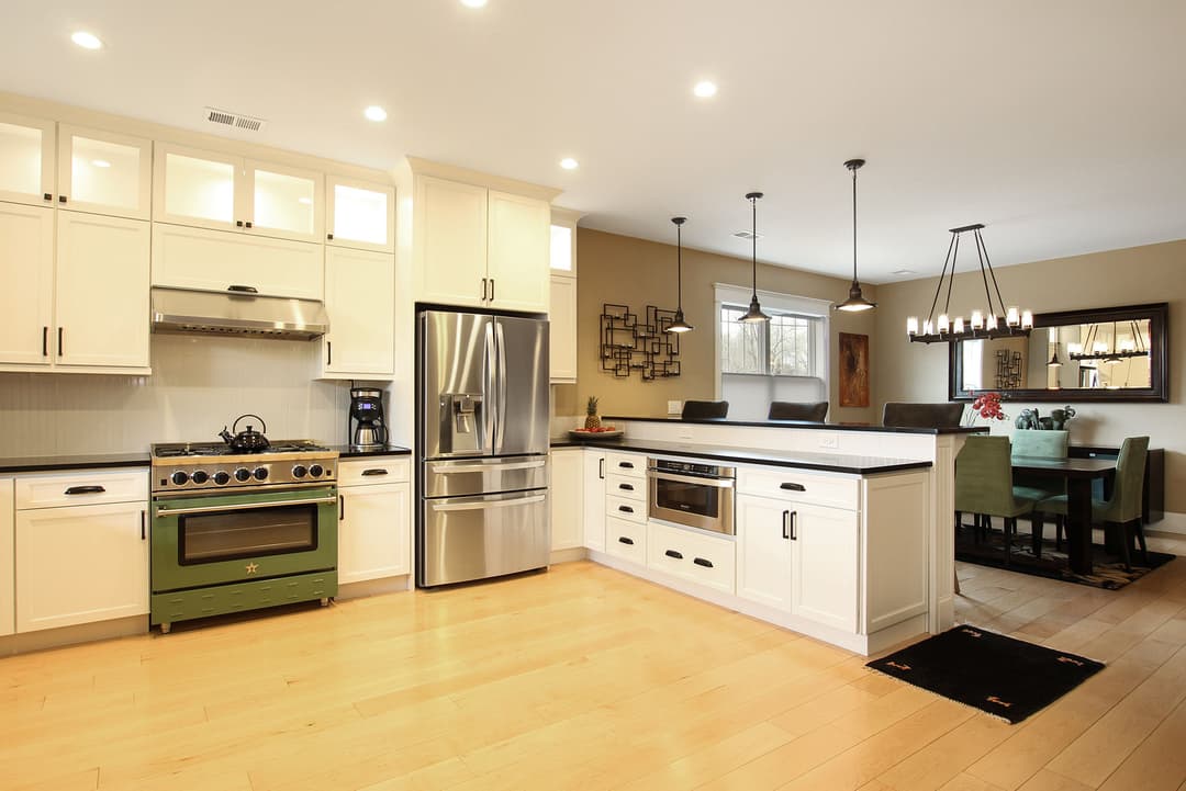 Modern kitchen with white cabinetry, stainless steel appliances, and a green vintage stove.