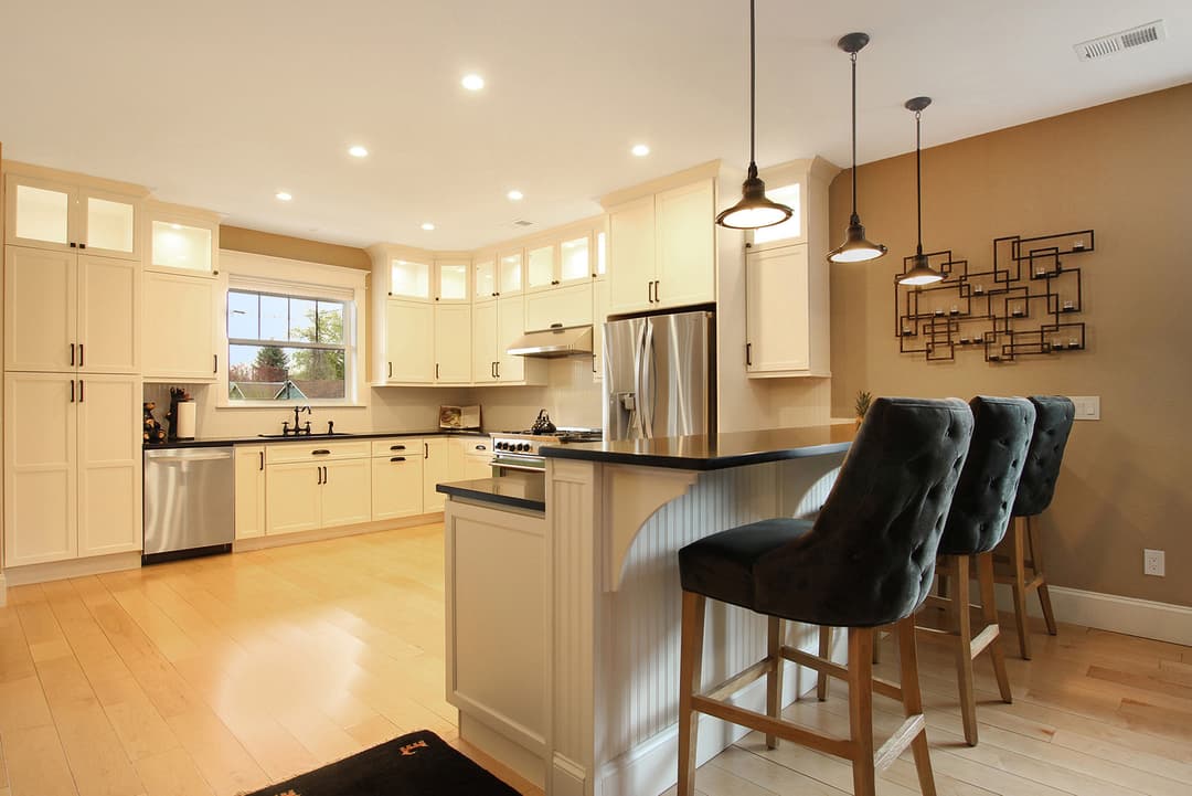 Modern kitchen with cream cabinets, stainless steel appliances, and stylish bar stools.