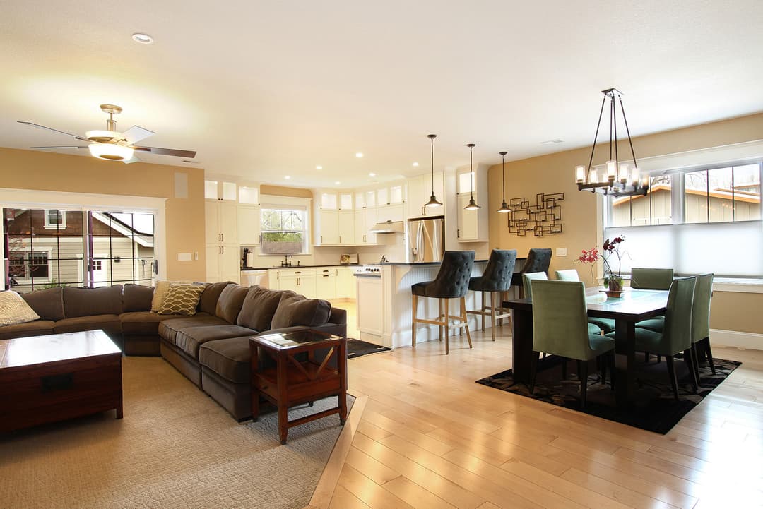 Modern open-concept living space with a cozy couch, dining area, and well-equipped kitchen.