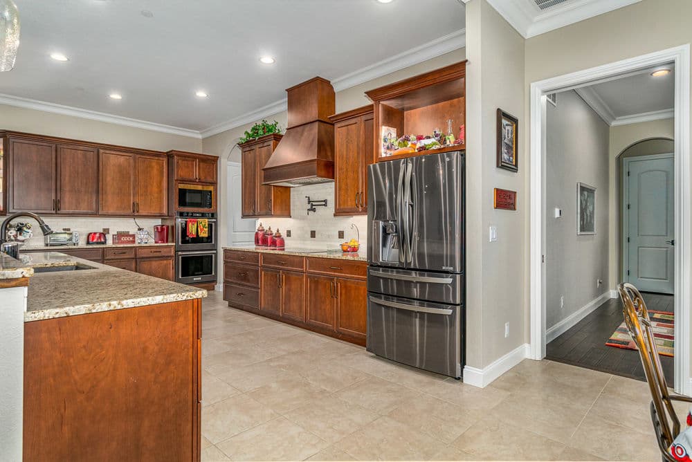 Modern kitchen with wooden cabinets, granite countertops, stainless steel appliances, and tile floor.