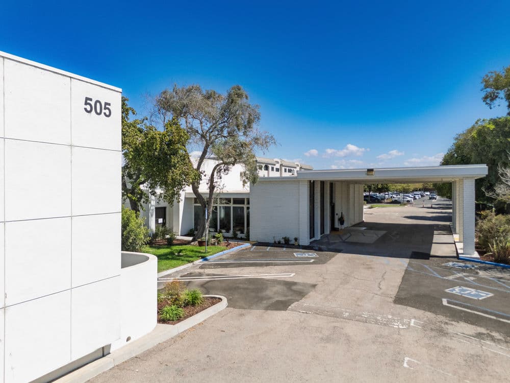 Modern building exterior at 505 with parking area and clear blue skies above.